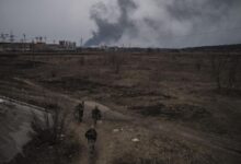 Soldiers walk on a path as smoke billows from the town of Irpin, on the outskirts of Kyiv, Ukraine, Saturday, March 12, 2022. (AP Photo/Felipe Dana)