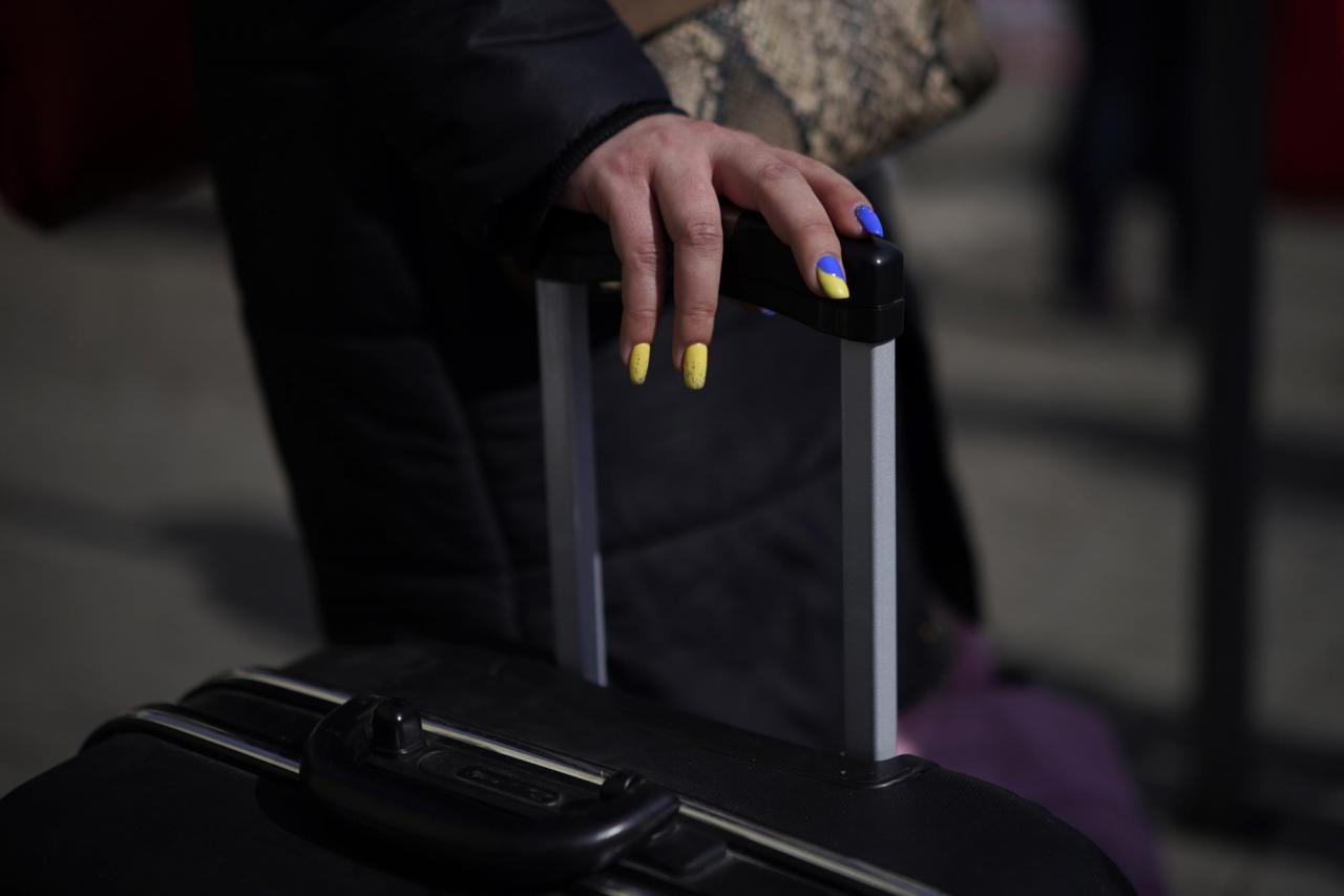 A refugee with painted fingernails for Ukraine holds a suitcase while waiting at the Przemysl train station, southeastern Poland, on Saturday, March 12, 2022. (AP Photo/Daniel Cole)