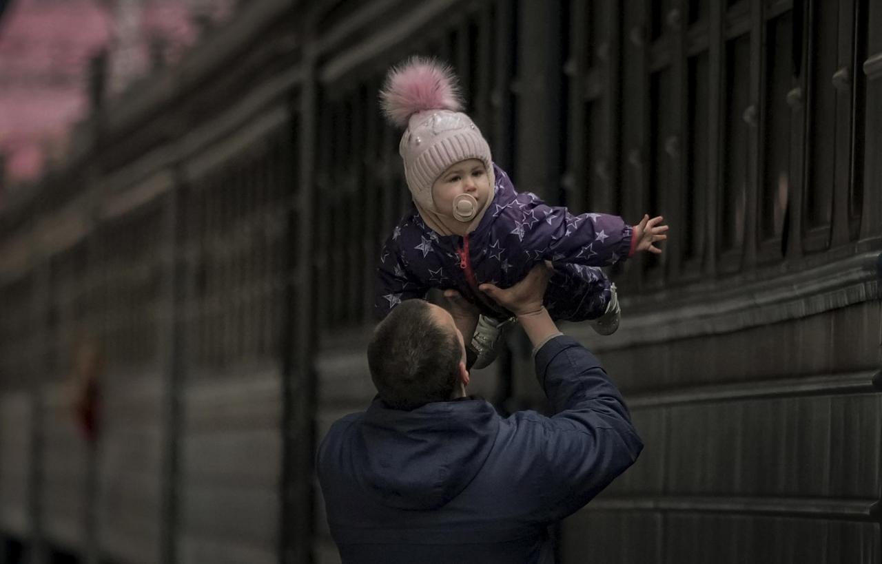 A man plays with a child before she boards a Lviv bound train, in Kyiv, Ukraine, March 12, 2022. (AP Photo/Vadim Ghirda)