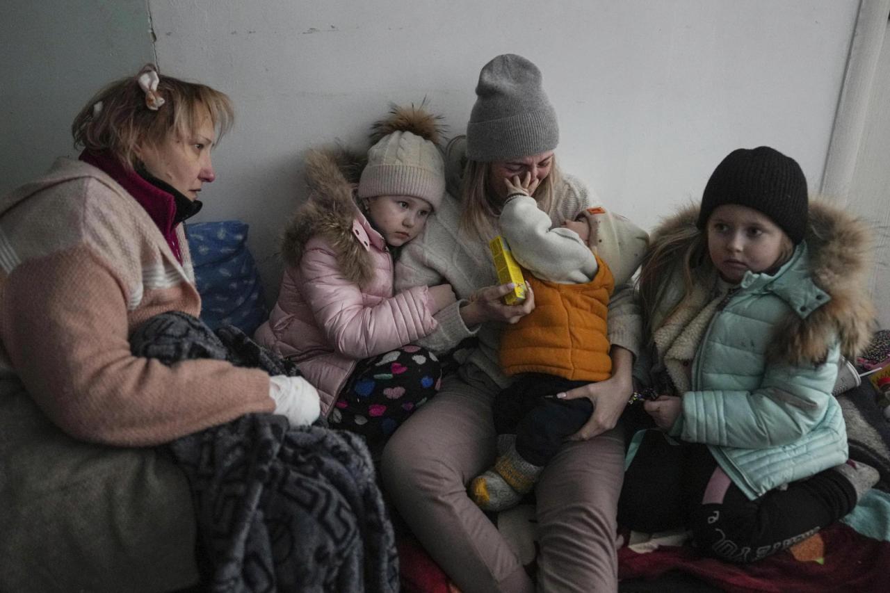 Women and children sit on the floor of a corridor in a hospital in Mariupol, eastern Ukraine Friday, March 11, 2022. (AP Photo/Evgeniy Maloletka)